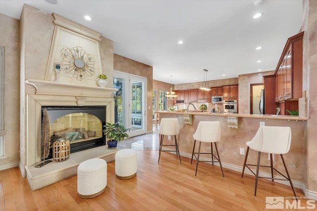 kitchen featuring light hardwood / wood-style floors, kitchen peninsula, stainless steel appliances, and a breakfast bar