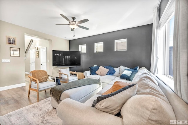 living room with light wood-type flooring, ceiling fan, and a healthy amount of sunlight