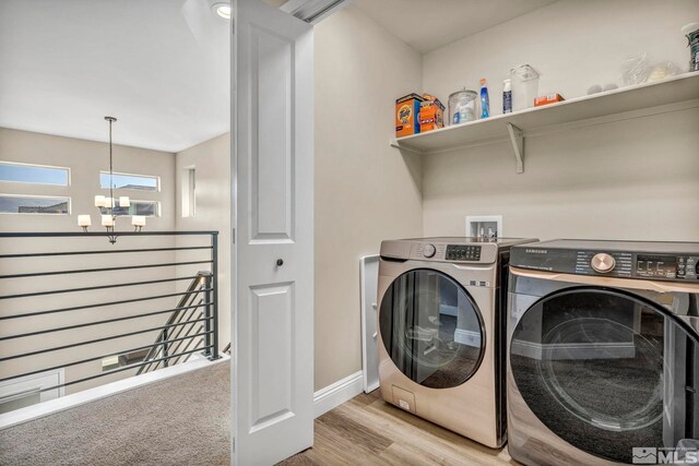 washroom with light wood-type flooring, washer and dryer, and a notable chandelier