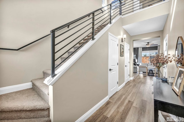 stairway with wood-type flooring and ceiling fan