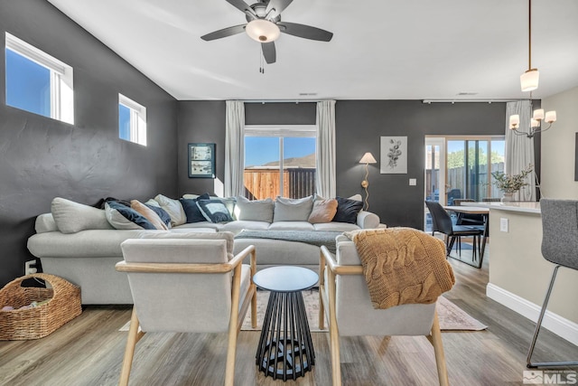 living room featuring ceiling fan with notable chandelier and wood-type flooring