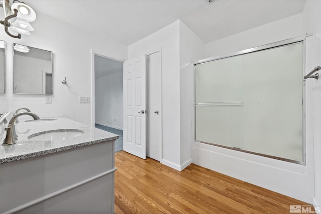 bathroom with bath / shower combo with glass door, vanity, and hardwood / wood-style flooring