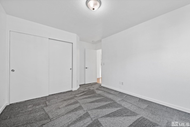 unfurnished bedroom featuring dark colored carpet and a closet