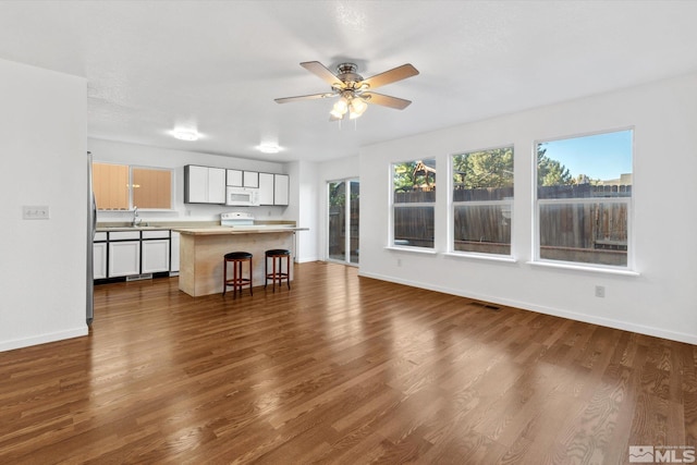 unfurnished living room with ceiling fan, sink, and dark wood-type flooring