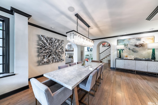 dining area with an inviting chandelier, wood-type flooring, and crown molding