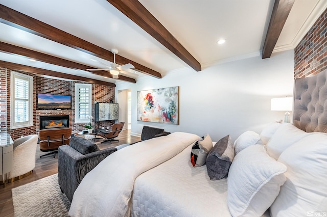 bedroom featuring brick wall, a brick fireplace, hardwood / wood-style floors, and ceiling fan