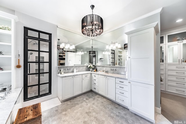 bathroom with an inviting chandelier, vanity, and backsplash