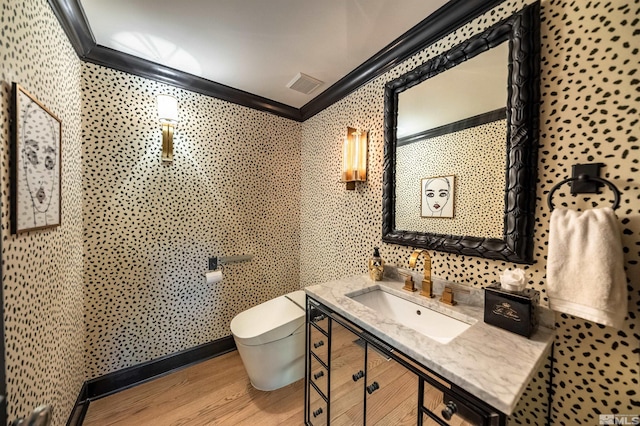 bathroom featuring hardwood / wood-style flooring, crown molding, vanity, and toilet