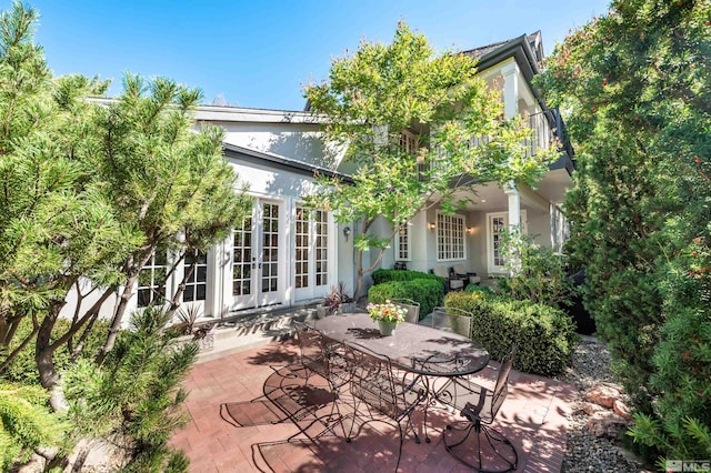 rear view of house with a balcony, a patio, and french doors