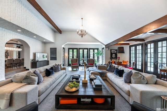 living room with vaulted ceiling with beams, an inviting chandelier, and french doors