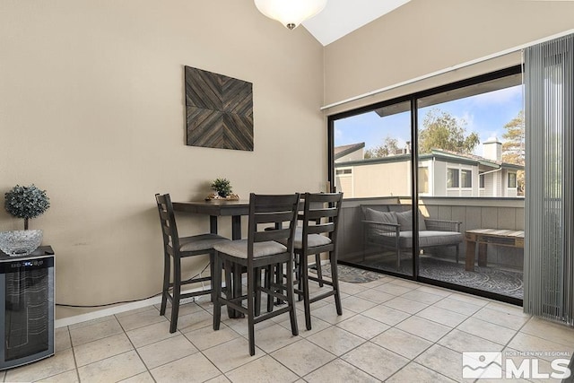 dining space with light tile patterned floors, beverage cooler, and lofted ceiling