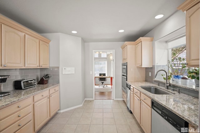 kitchen with light stone counters, light brown cabinets, light tile patterned floors, stainless steel appliances, and sink