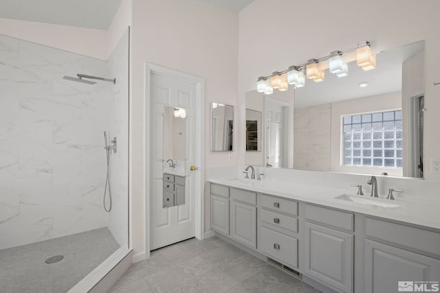 bathroom with tiled shower and vanity