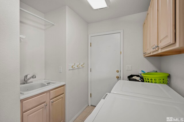 laundry area with light tile patterned floors, separate washer and dryer, cabinets, and sink