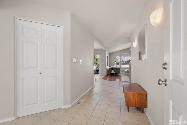 hallway with lofted ceiling and light tile patterned flooring