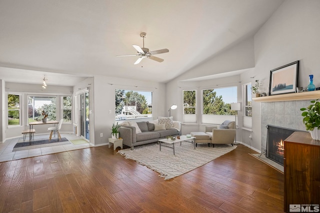 living room with ceiling fan, hardwood / wood-style flooring, high vaulted ceiling, and a tile fireplace