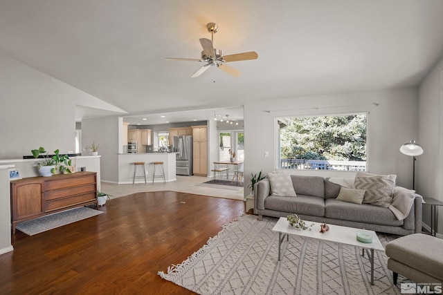 living room featuring vaulted ceiling, ceiling fan, and light hardwood / wood-style flooring