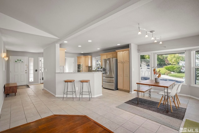 kitchen featuring light tile patterned floors, appliances with stainless steel finishes, kitchen peninsula, and lofted ceiling