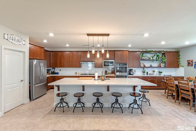 kitchen featuring appliances with stainless steel finishes, a kitchen island with sink, and pendant lighting