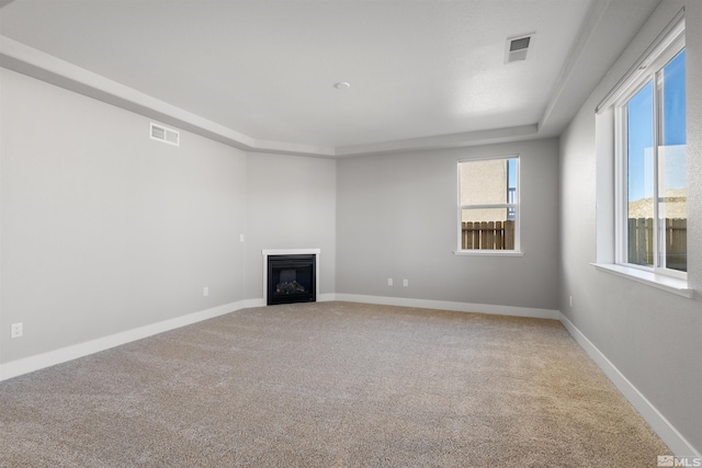 unfurnished living room featuring carpet and a tray ceiling