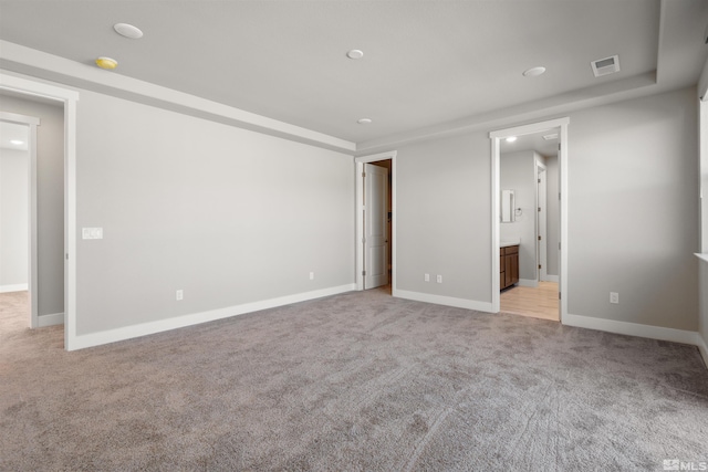 unfurnished bedroom featuring light carpet and ensuite bathroom