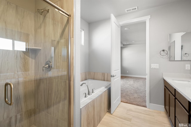 bathroom featuring hardwood / wood-style flooring, vanity, and separate shower and tub