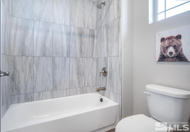 bathroom featuring toilet and tiled shower / bath