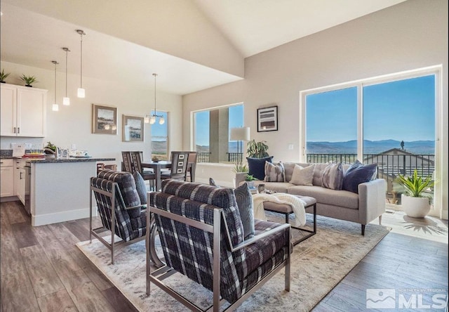 living room featuring dark hardwood / wood-style flooring, high vaulted ceiling, a mountain view, and a notable chandelier