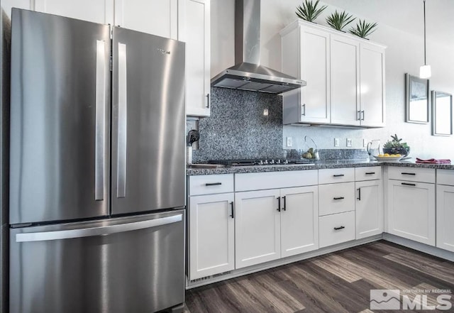 kitchen with decorative light fixtures, wall chimney exhaust hood, dark wood-type flooring, white cabinetry, and stainless steel refrigerator