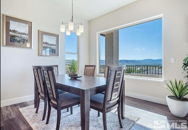 dining area with wood-type flooring, a mountain view, and a notable chandelier