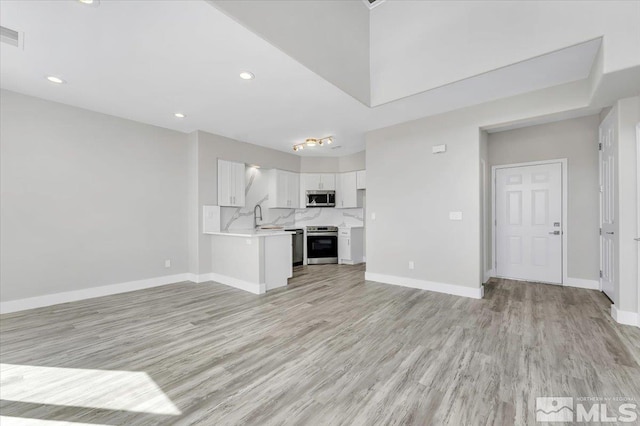 unfurnished living room with sink and light hardwood / wood-style flooring