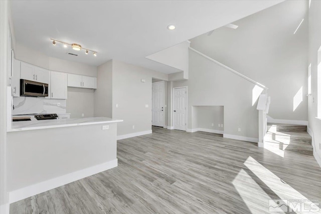 kitchen with kitchen peninsula, tasteful backsplash, light hardwood / wood-style flooring, and white cabinets