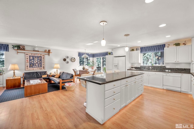 kitchen featuring white cabinets, dishwasher, hanging light fixtures, and a wealth of natural light