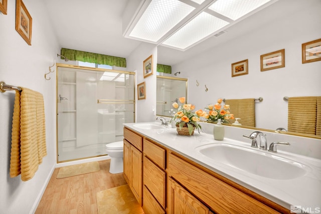 bathroom featuring hardwood / wood-style floors, walk in shower, vanity, and toilet