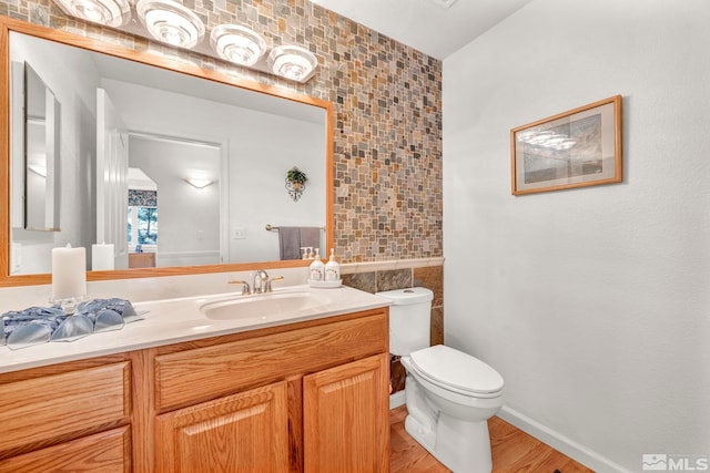 bathroom with tile walls, vanity, toilet, and hardwood / wood-style flooring