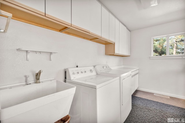 laundry room with hardwood / wood-style flooring, sink, washer and dryer, and cabinets