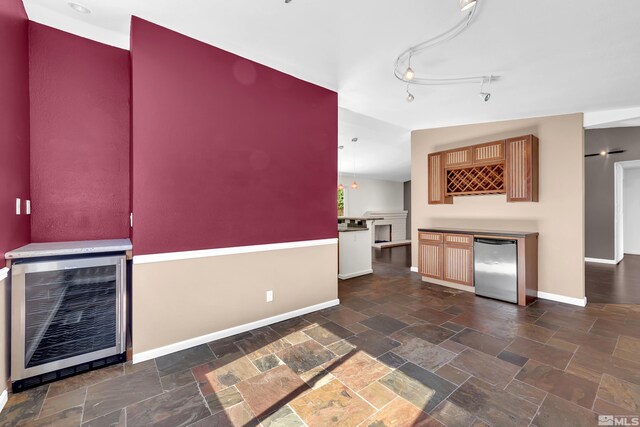 kitchen featuring beverage cooler, stainless steel refrigerator, vaulted ceiling, and track lighting