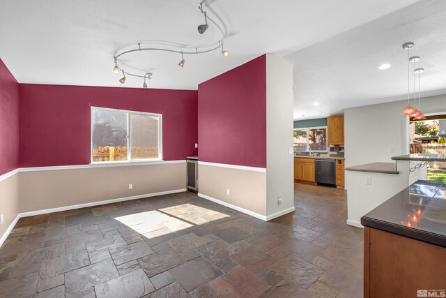 unfurnished dining area with rail lighting and vaulted ceiling