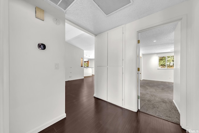 hallway with a textured ceiling and dark hardwood / wood-style floors