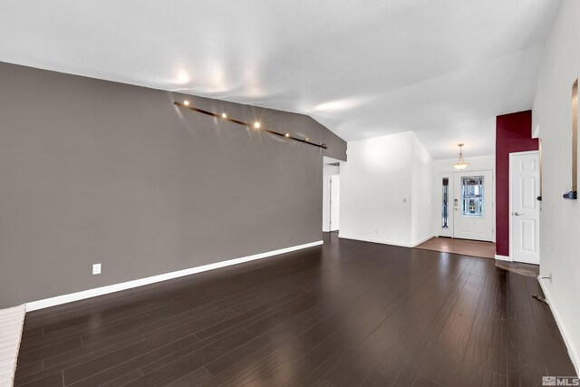 unfurnished living room featuring lofted ceiling and dark wood-type flooring