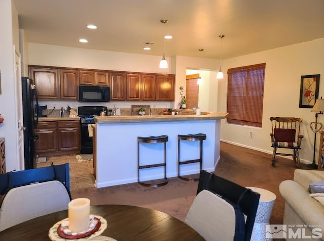 kitchen featuring pendant lighting, black appliances, and light colored carpet