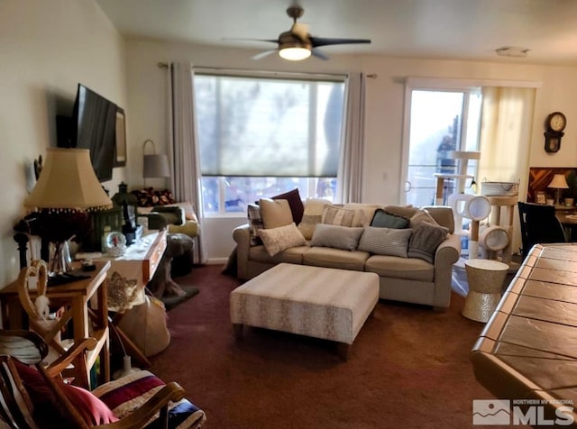 living room featuring ceiling fan, dark carpet, and a wealth of natural light