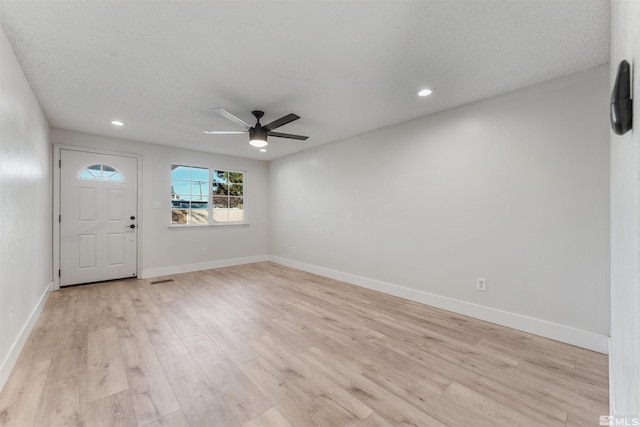 interior space with a textured ceiling, ceiling fan, and light hardwood / wood-style flooring