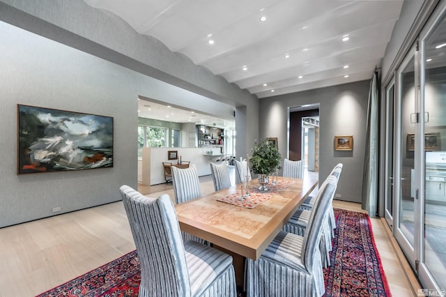 dining space with beam ceiling and light hardwood / wood-style floors