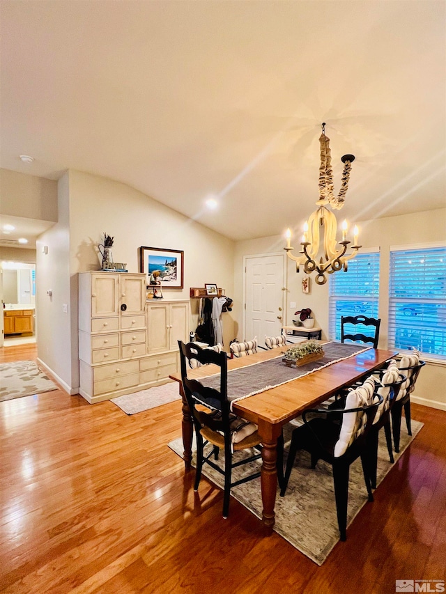 dining space with a chandelier, vaulted ceiling, and hardwood / wood-style floors