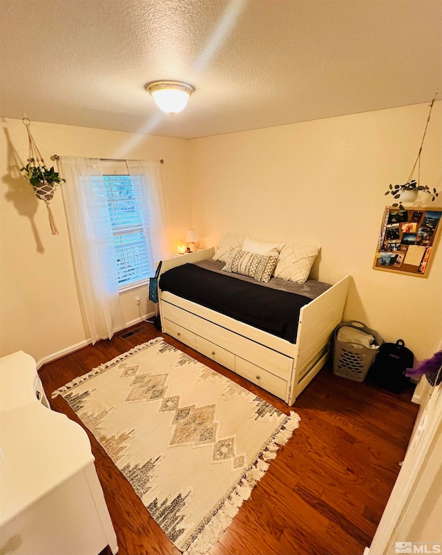 bedroom featuring a textured ceiling and dark hardwood / wood-style floors