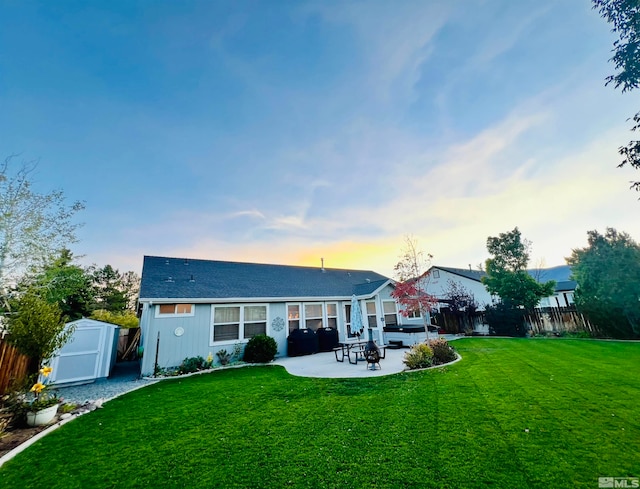 back house at dusk with a patio and a yard