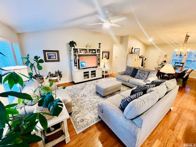 living room featuring ceiling fan with notable chandelier, vaulted ceiling, and hardwood / wood-style floors