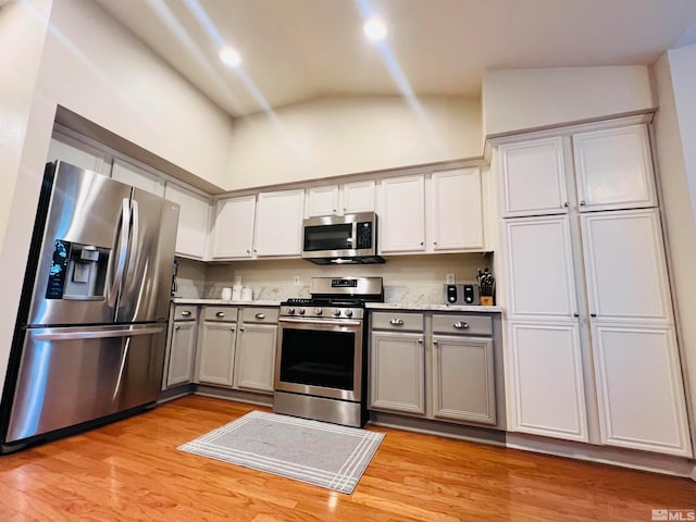 kitchen featuring appliances with stainless steel finishes, light hardwood / wood-style floors, lofted ceiling, and gray cabinets