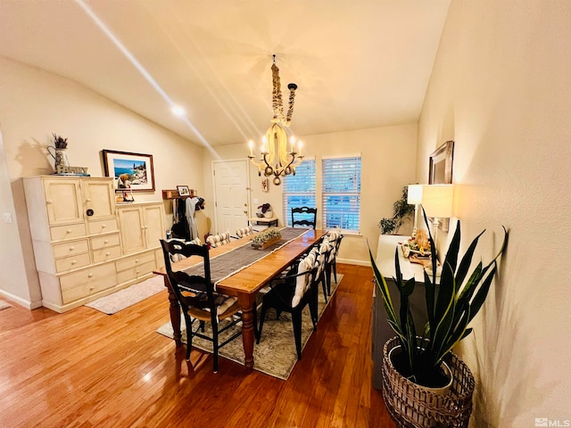 dining area with wood-type flooring, lofted ceiling, and a chandelier